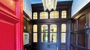 Una puerta de madera oscura con paneles de vidrio y un candelabro colgando sobre ella.