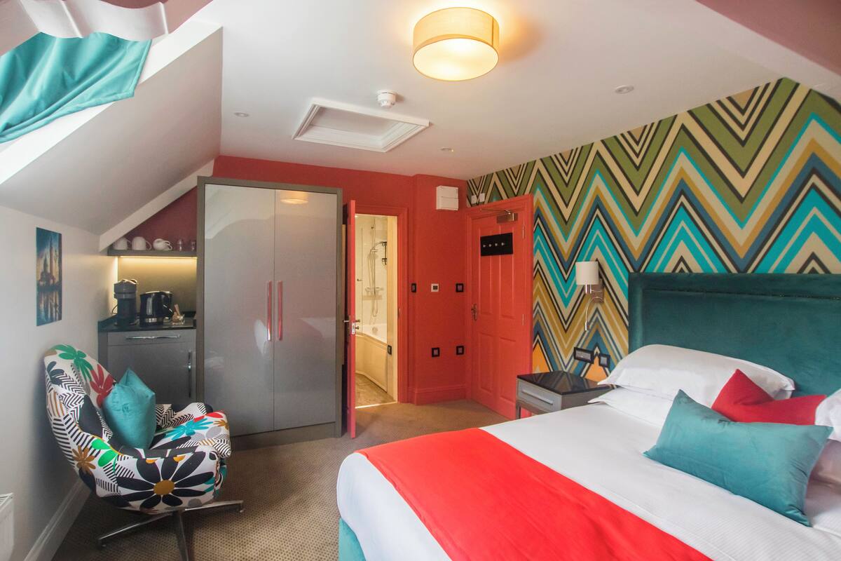 A hotel room with a bed, a desk, a chair, a wardrobe, and a bathroom.