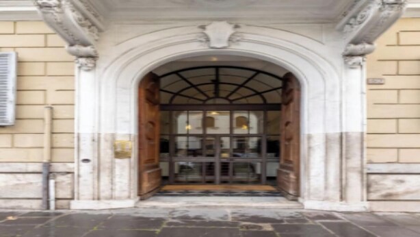 A building entrance with an arched doorway, a tiled floor, and a wooden door. - Cozy and Stylish 2-Bedroom Apartment in Central Rome
 (Roma)