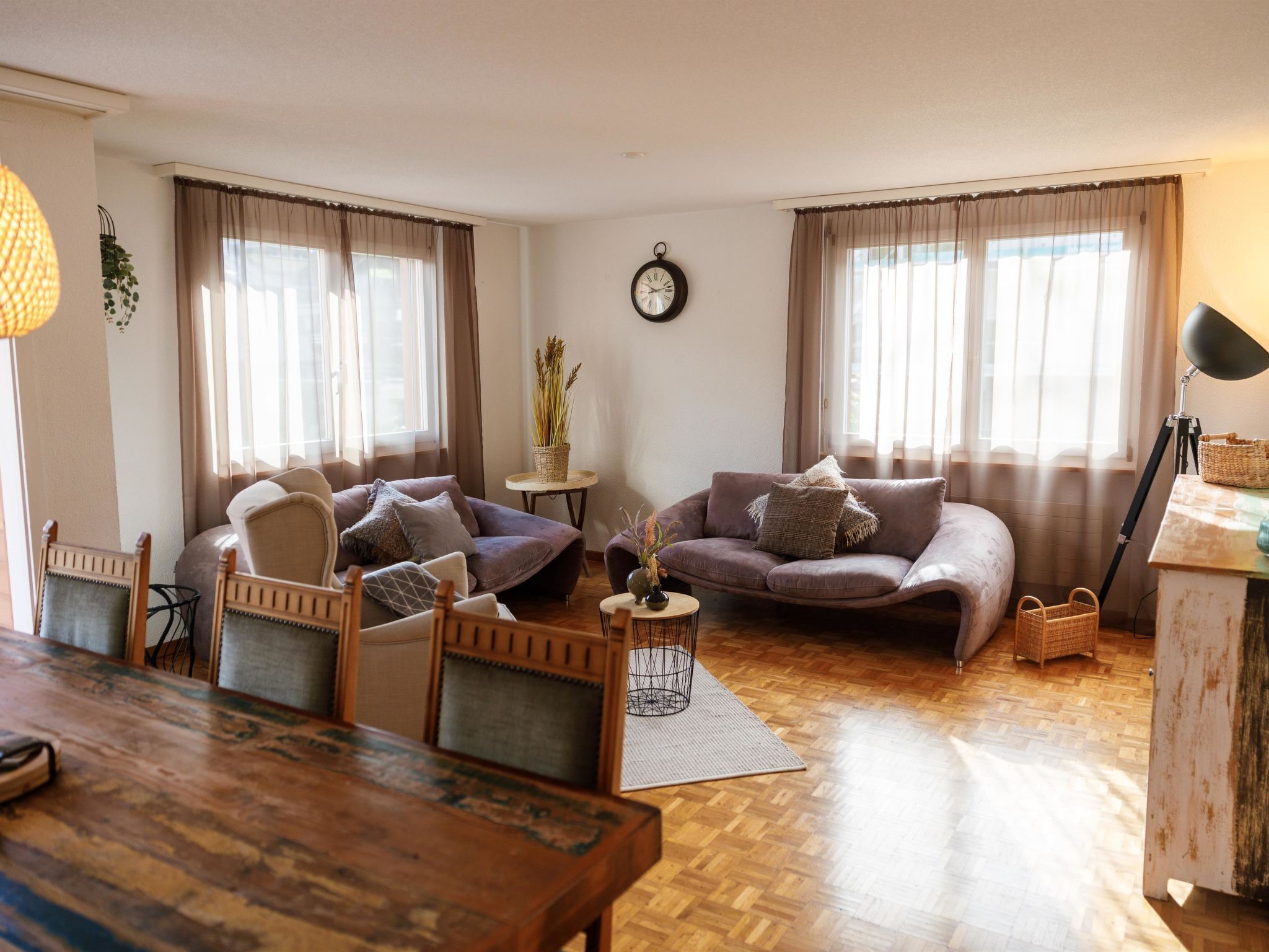 Ein gemütliches Wohnzimmer mit einem Holzesstisch, zwei Sofas und einem kleinen Beistelltisch mit einer Pflanze.
