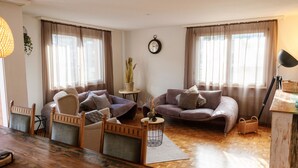 A cozy living room with a wooden dining table, two sofas, and a small side table with a plant. - Mountain View by Interhome (Frutigen)