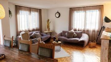 Ein gemütliches Wohnzimmer mit einem Holzesstisch, zwei Sofas und einem kleinen Beistelltisch mit einer Pflanze.