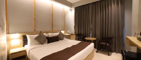 A hotel room with a large bed, bedside tables, a desk, and a chair.