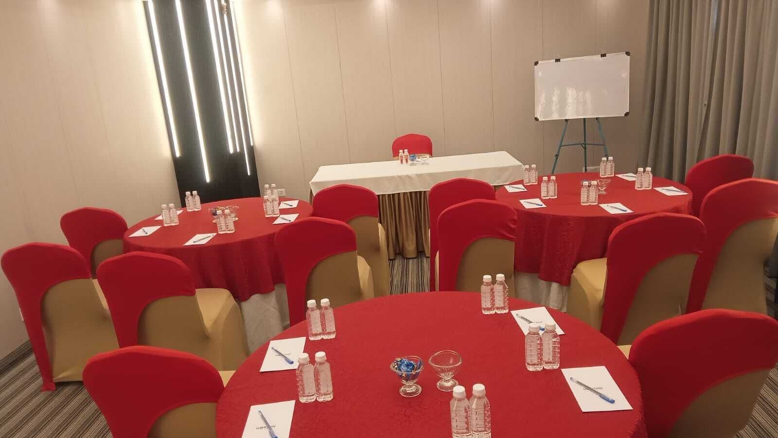 A conference room with multiple tables, red chairs, and a whiteboard.