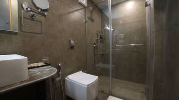Ein modernes Badezimmer mit einer gläsernen Duschkabine, einer weißen Toilette und einer Marmorarbeitsplatte.