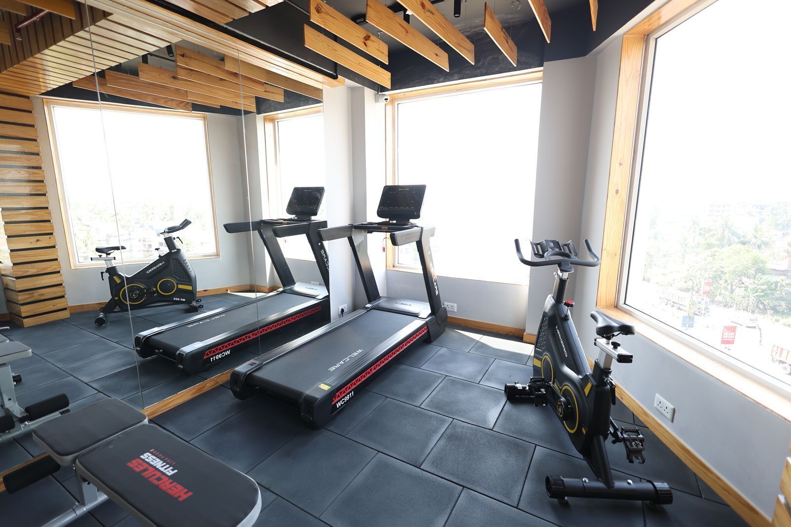 Un gimnasio con cintas de correr, bicicletas estáticas y bancos de pesas.