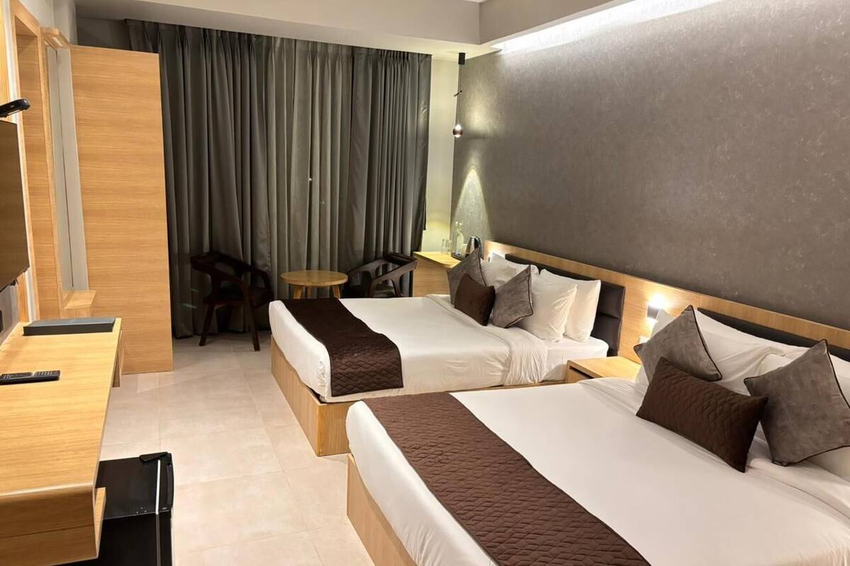 Une chambre d’hôtel avec deux lits, un bureau, une chaise et une petite table.
