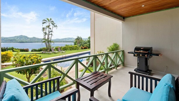 Ein Balkon mit Blick auf einen See und Berge, einem Grill und Sitzmöbeln im Freien.