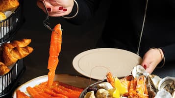 Una fuente de mariscos con salmón, camarones, almejas y ostras, y una cesta de croissants.