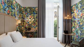 A hotel room with a large bed, a desk with a laptop, and a chair.