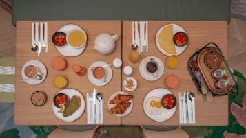 A breakfast table set with plates of food, cups, and cutlery.