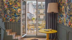 A room with a balcony, a yellow table, wicker chairs, and a patterned wall. - Miss Fuller (Paris)