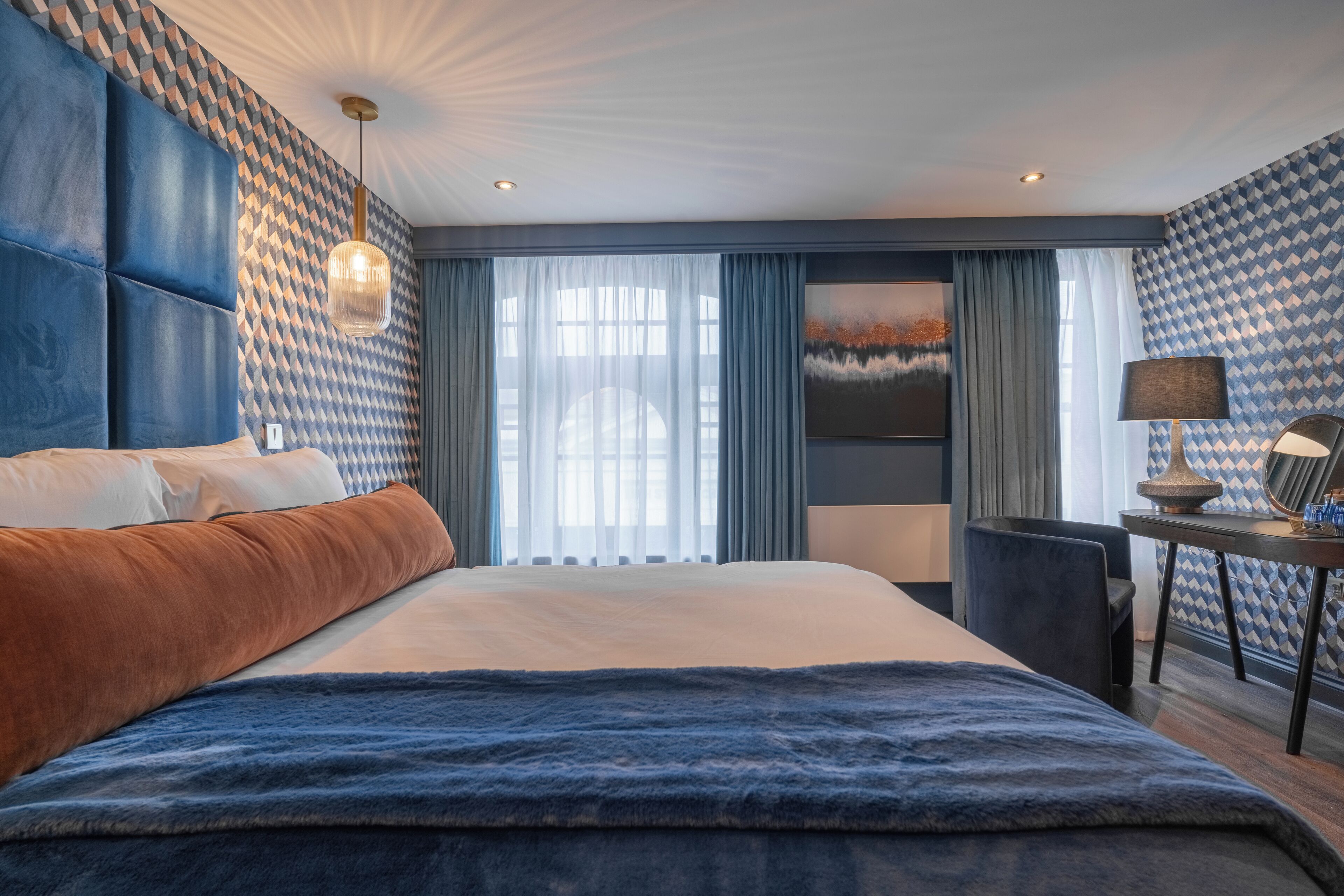 Une chambre d’hôtel moderne, dotée d’un grand lit, d’un bureau et offrant une vue sur l’extérieur.