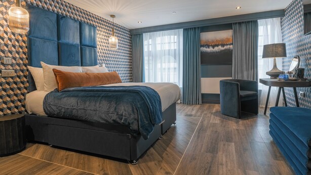 A modern hotel room with a large bed, a desk, and a chair. - Howfield Hotel (Merthyr Tydfil)