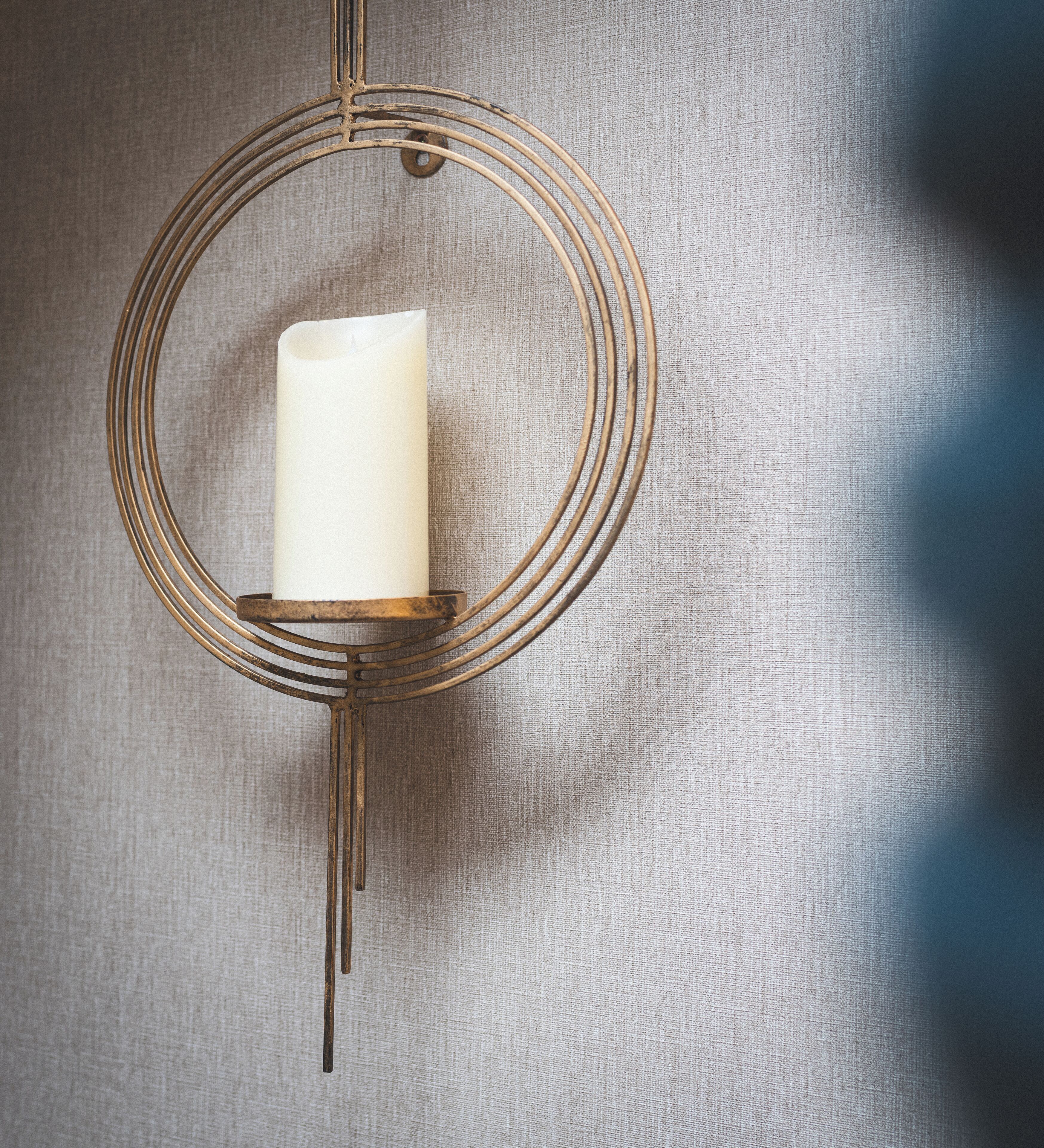 A wall-mounted candle holder with a white candle.