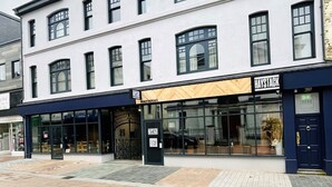 A multi-story building with a white facade and black trim. It features a storefront with a sign that reads "Haystack Cafe." - Howfield Hotel (Merthyr Tydfil)