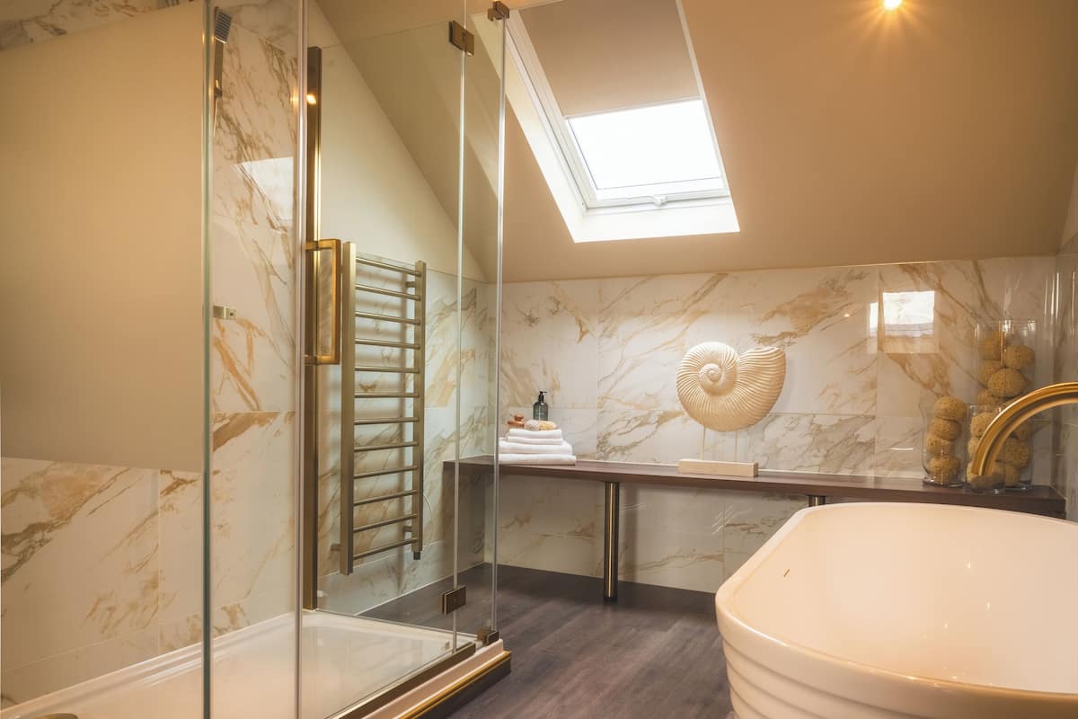 Un baño moderno con ducha de vidrio, una bañera independiente y un tragaluz.