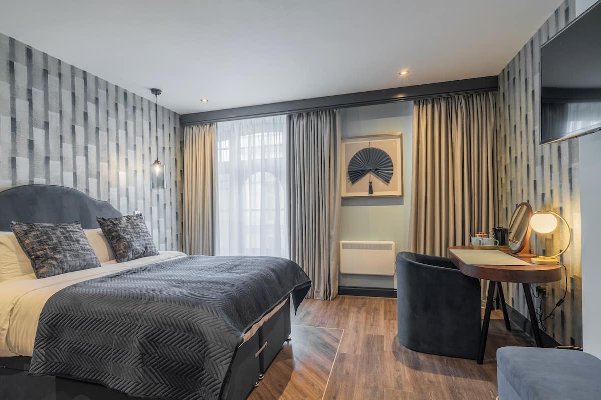 Un dormitorio moderno con cama, mesita de noche y escritorio con lámpara.
