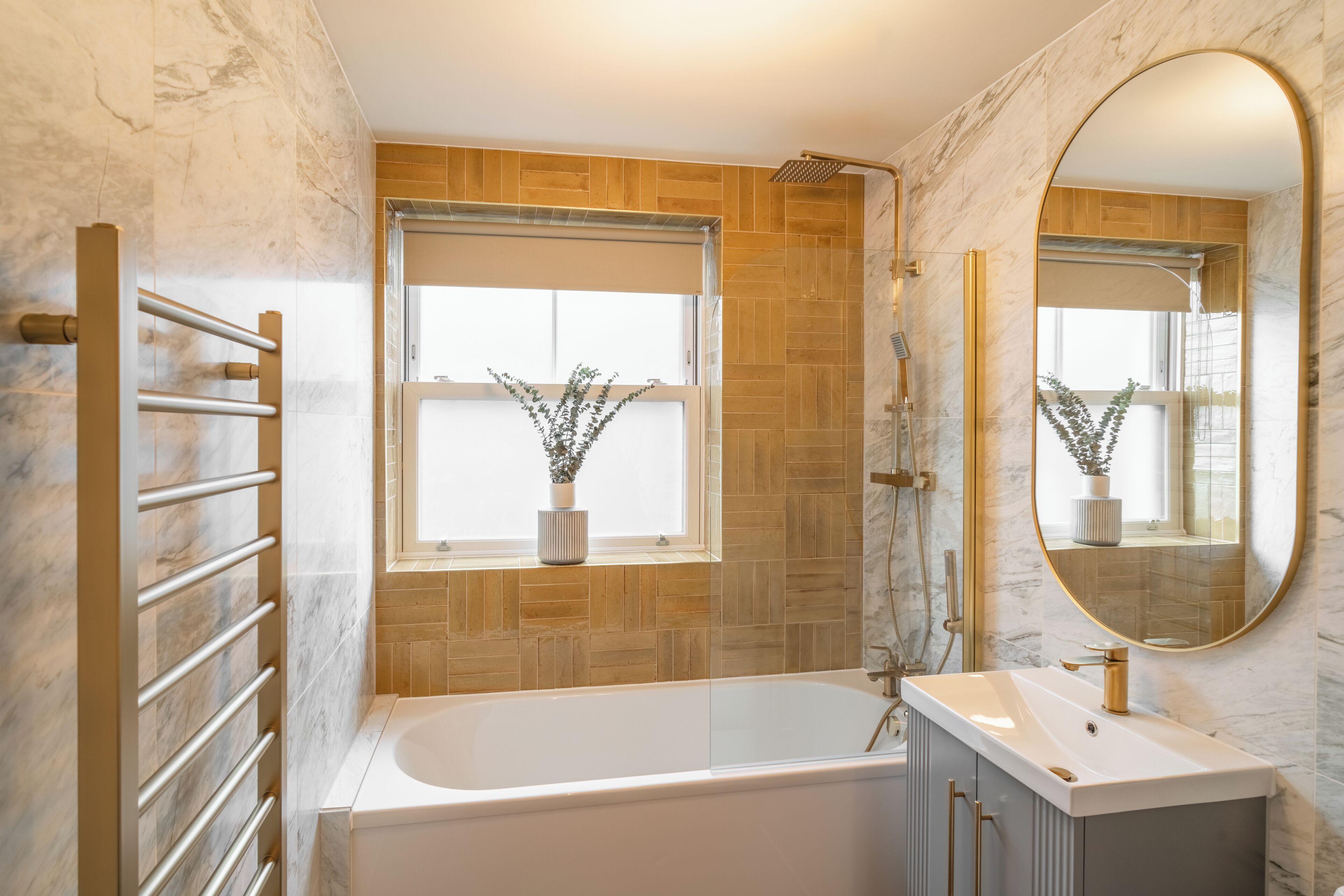 Ein modernes Badezimmer mit einer freistehenden Badewanne, einem großen Spiegel und einem Fenster mit einer Pflanze.