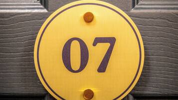 Une sonnette jaune avec le numéro 07, fixée sur une porte en bois sombre.