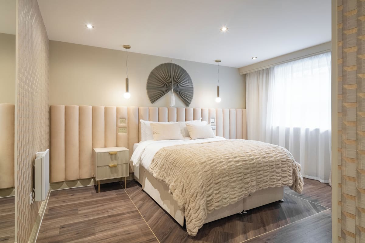 Un dormitorio moderno con una cama grande, mesitas de noche y un ventilador en la pared.
