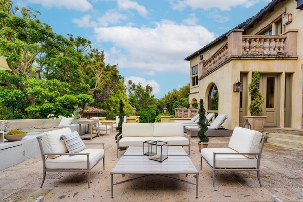 An outdoor patio with white sofas, a coffee table, and a dining area.