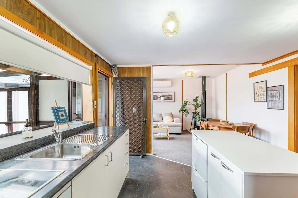 A modern kitchen with a sink, countertop, and cabinets. There is a dining area with a table and chairs.