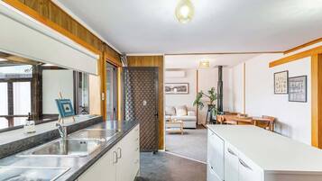 A modern kitchen with a sink, countertop, and cabinets. There is a dining area with a table and chairs.