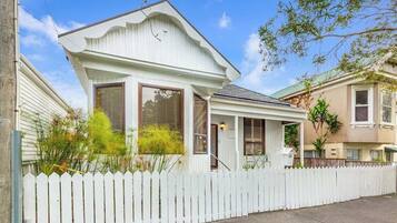 A single-story house with a white picket fence, a covered porch, and a front door.