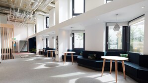 Un intérieur moderne avec un plafond haut, de grandes fenêtres et un espace salon avec des tables.