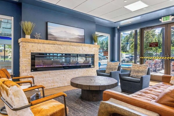 A lobby with a stone fireplace, comfortable seating, and large windows offering a view of the outdoors.