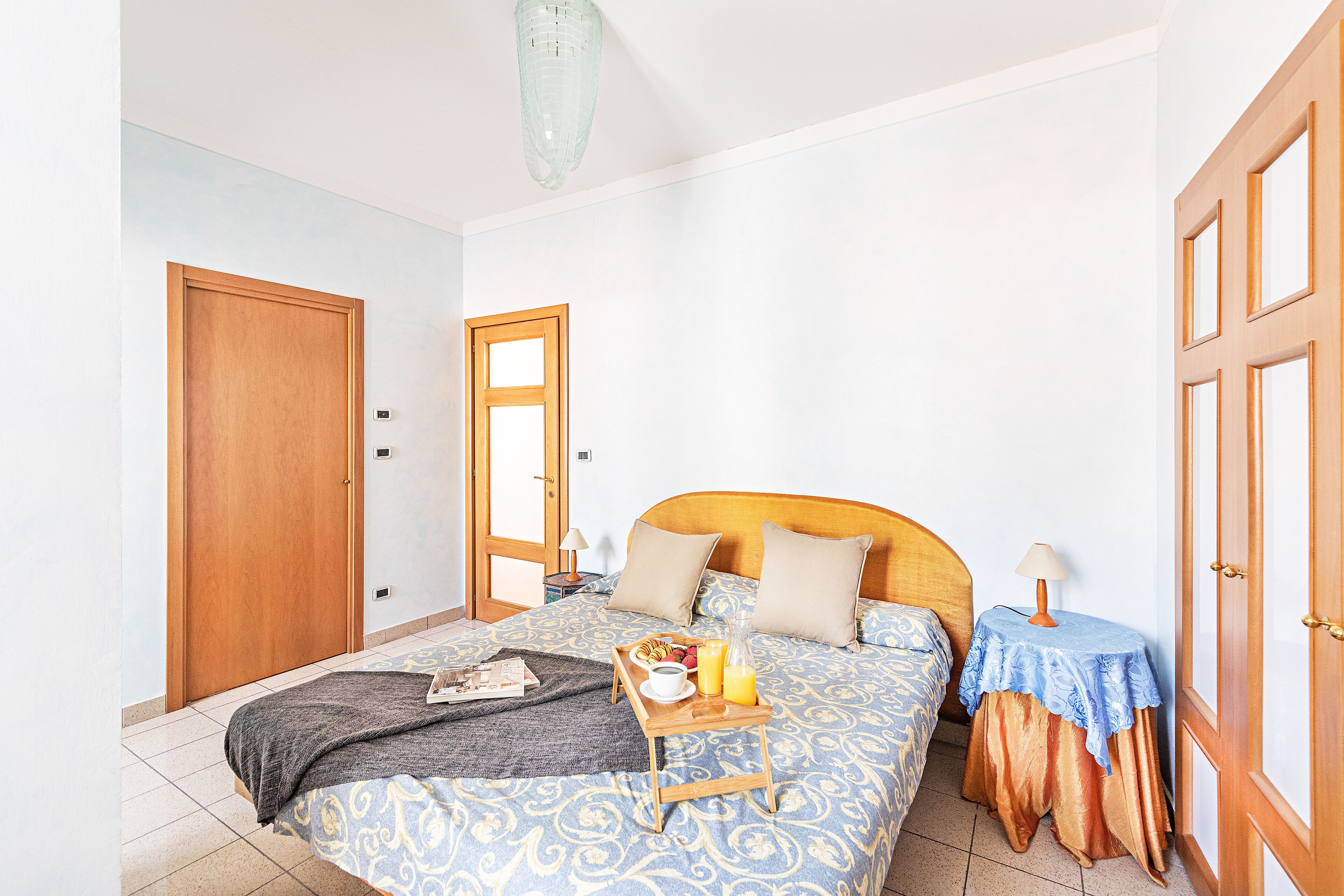 Ein Schlafzimmer mit einem Bett, Nachttischen, einer Holztür und einer Lampe.