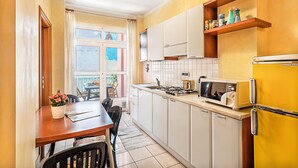A kitchen with white cabinets, a yellow refrigerator, and a window with curtains. - Gaudio Charming Apartment by Wonderful Italy (Sanremo)