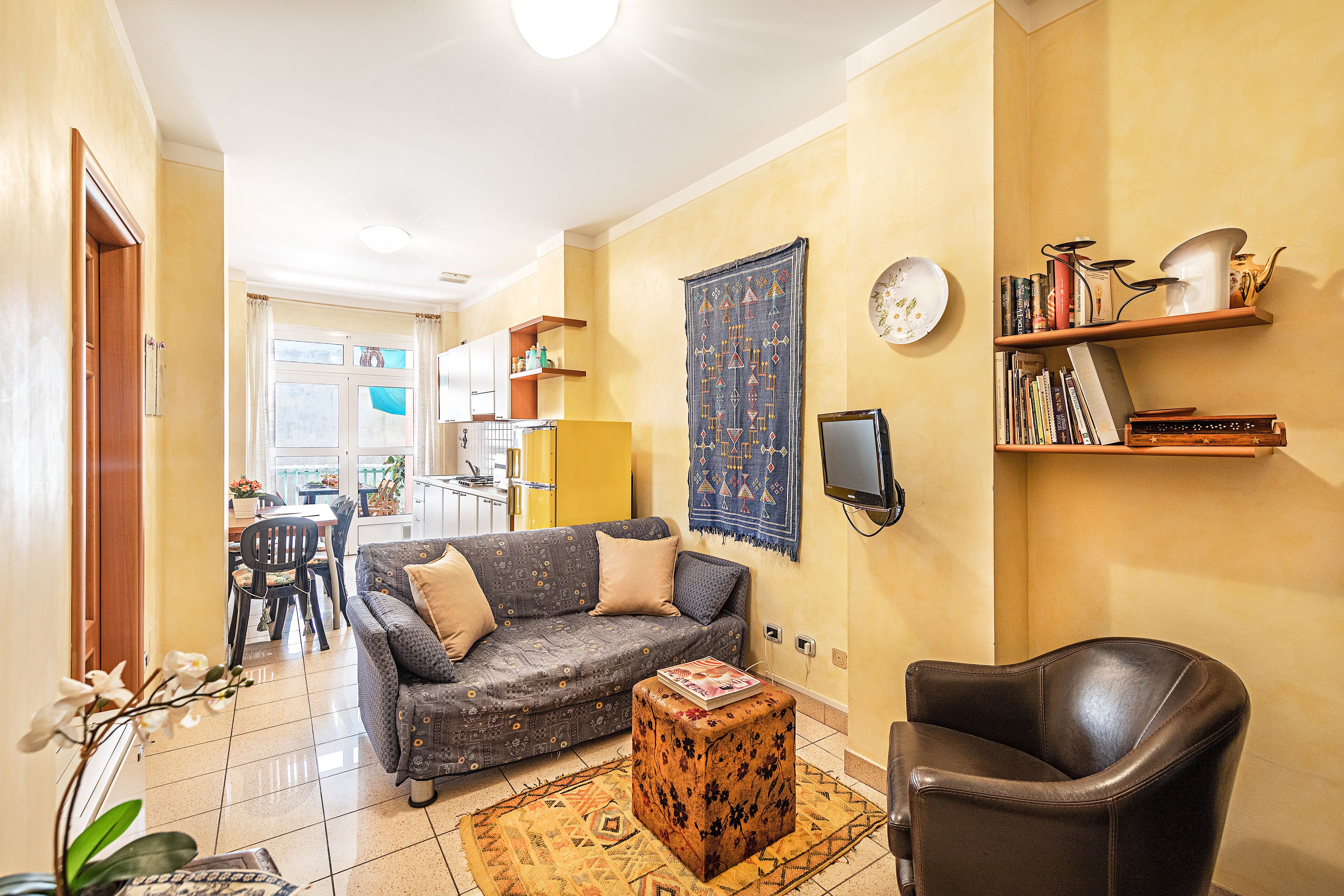 A living room with a sofa, a coffee table, a leather armchair, and a bookshelf.