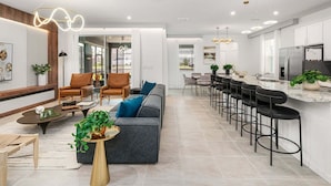 Una cocina moderna con barra, zona de estar con sofás y sillas, y mesa de comedor.
