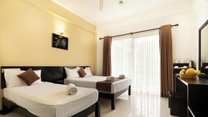 Habitación de hotel con dos camas, un escritorio, un espejo y una cesta de frutas.
