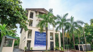 Un edificio de varios pisos con un cartel grande que anuncia servicios como piscina, comida y bebidas, alojamiento, banquetes y excursiones.