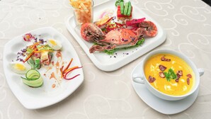Una mesa con tres platos: un plato de mariscos, un tazón de sopa y un plato con vegetales y un huevo cocido.
