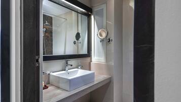 A modern bathroom with a white sink, a large mirror, and a shower.