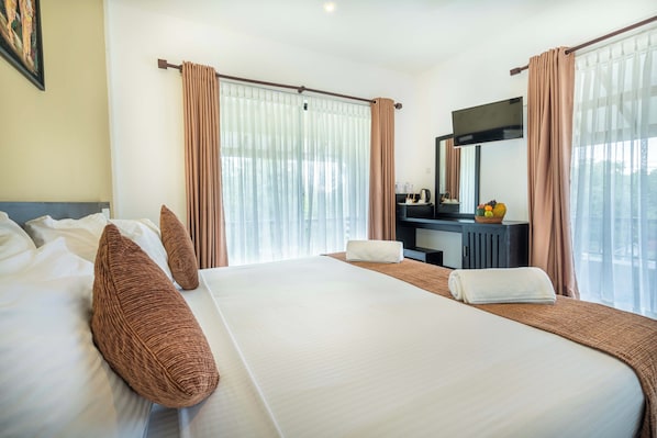 Habitación de hotel con una cama grande, un escritorio, un espejo y vistas al exterior.