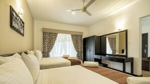 Habitación de hotel con dos camas, televisión de pantalla plana, armario y ventilador de techo.