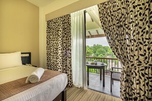 A hotel room with a bed, a small table with tea set, and a balcony with a view of greenery. - Lavendish Tamarind Lifestyle (Kataragama)