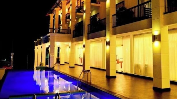 Un hotel con piscina, varios balcones e iluminación cálida.