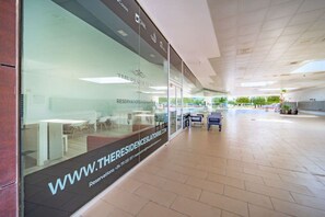 Un vestíbul d'hotel modern amb façana de vidre, una recepció i una zona àmplia amb seients.