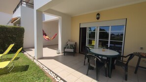 A patio area with a table and chairs, a hammock, and a chair with a leaf-patterned cushion. - Sand, Sea and Salt - Alvor (Alvor)