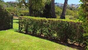 A well-maintained garden with two tall palm trees, a neatly trimmed hedge, and a grassy area. - Sand, Sea and Salt - Alvor (Alvor)