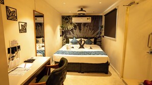 Een hotelkamer met een bed, bureau, stoel, airconditioning en een raam.