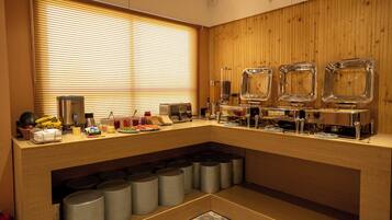 A breakfast bar with a wooden backdrop, a window with blinds, and various breakfast items.