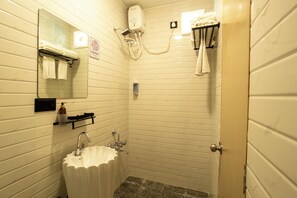A small, compact bathroom with a sink, mirror, towel rack, and a shower head. - Click Hotel (Mundra)