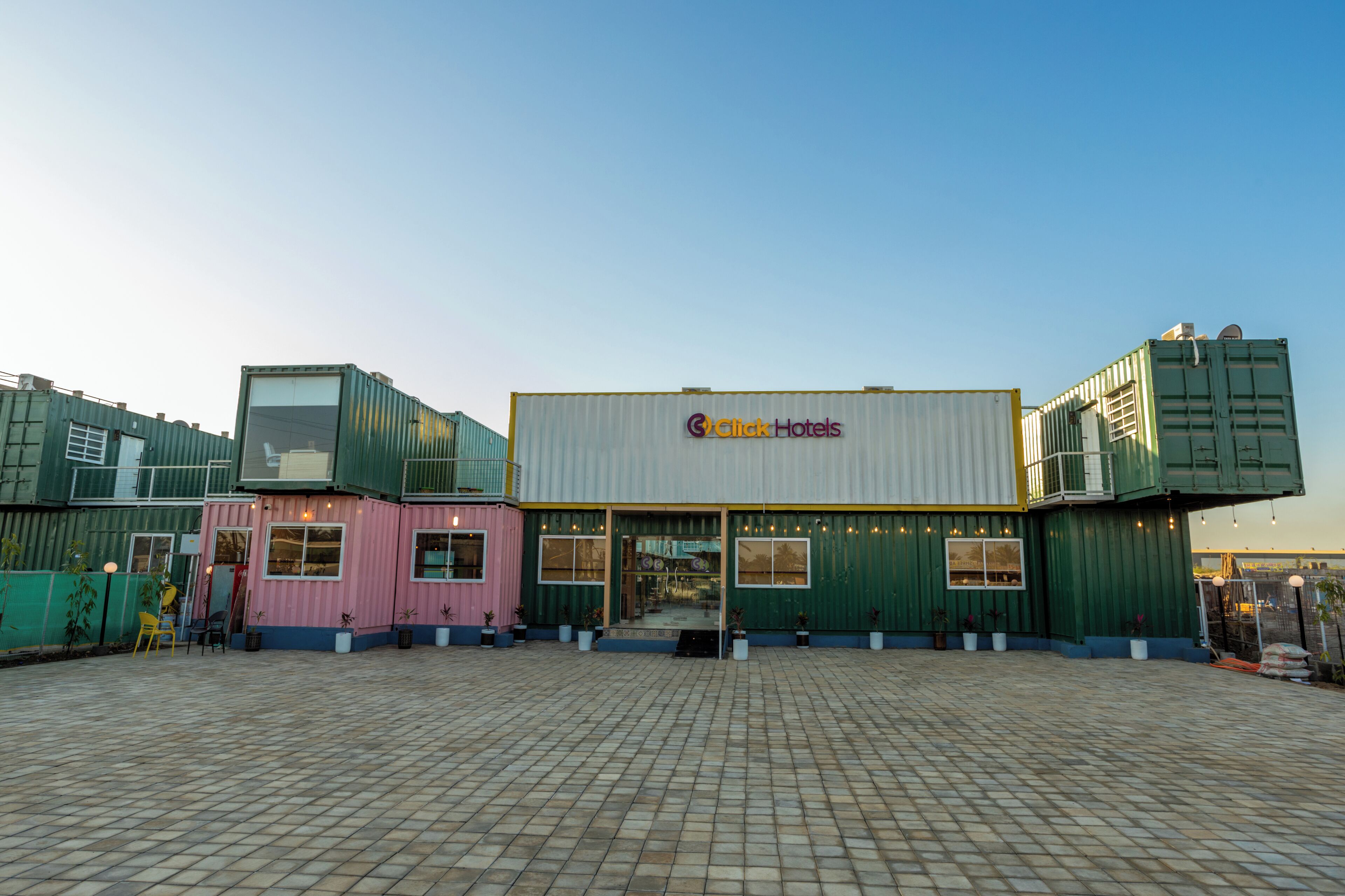 A hotel with a modern design, featuring a prominent sign and a spacious outdoor area with a tiled floor.